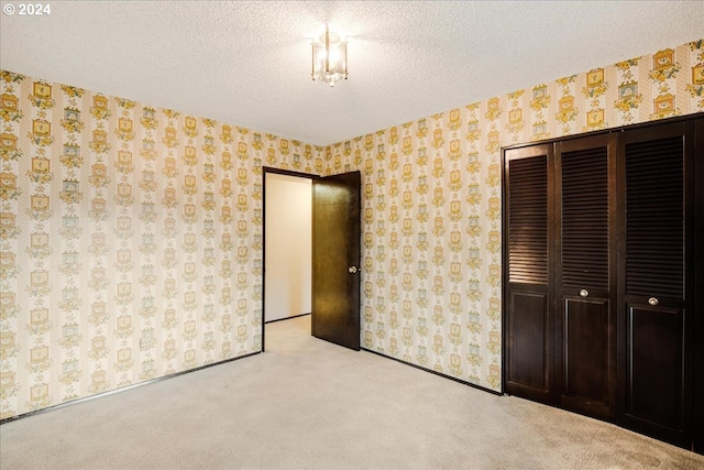 unfurnished bedroom featuring a textured ceiling, light carpet, and a closet