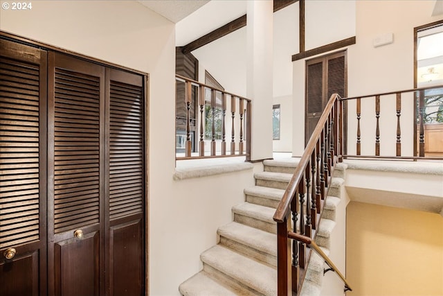 staircase with beam ceiling and high vaulted ceiling