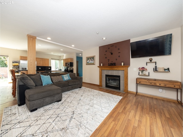 living room featuring light hardwood / wood-style flooring, plenty of natural light, and a tile fireplace