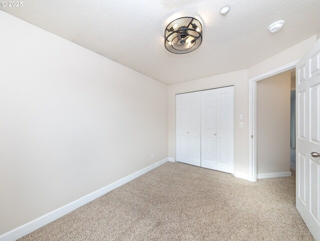 unfurnished bedroom with a closet, a textured ceiling, and carpet flooring