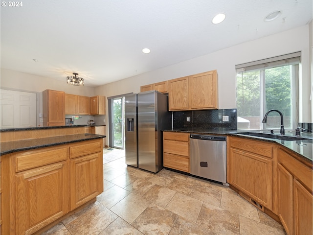 kitchen featuring appliances with stainless steel finishes, light tile patterned floors, dark stone countertops, and sink