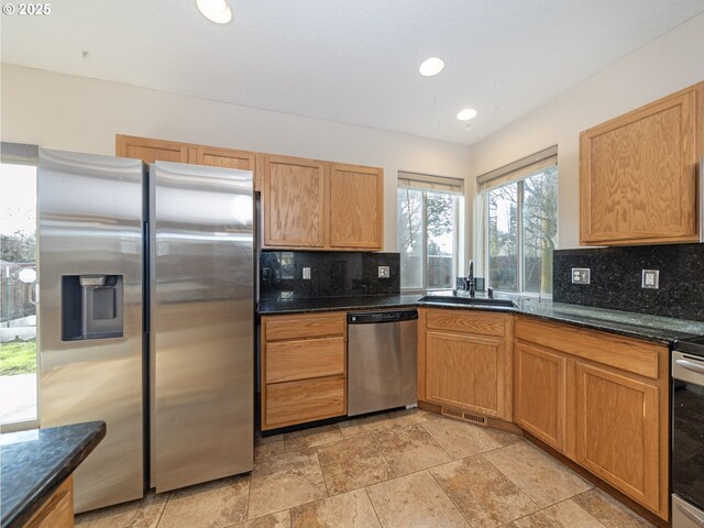 kitchen featuring tasteful backsplash, appliances with stainless steel finishes, sink, and dark stone countertops