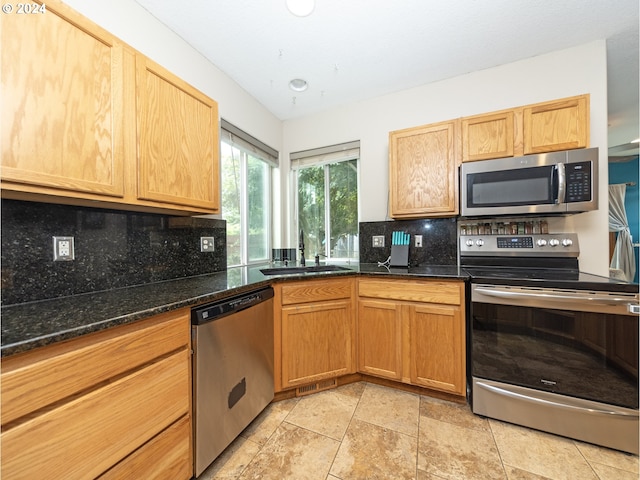 kitchen featuring appliances with stainless steel finishes, light tile patterned floors, sink, and backsplash