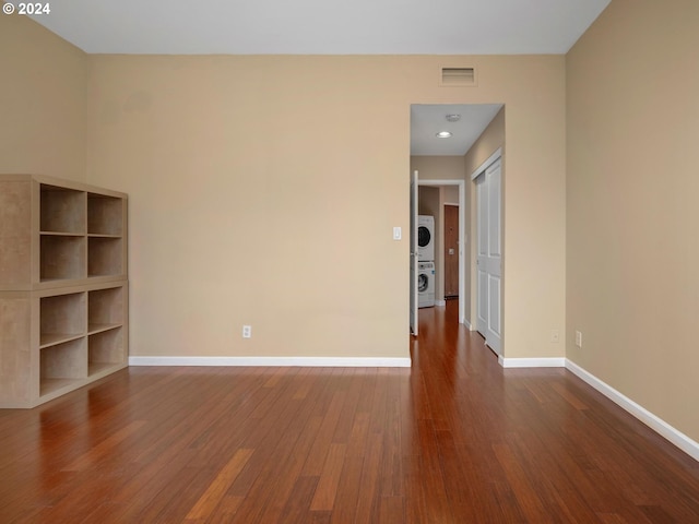 empty room with stacked washer / dryer and hardwood / wood-style flooring