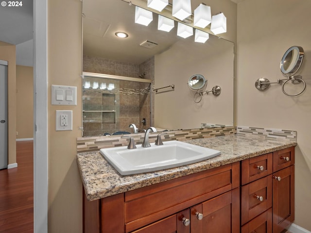 bathroom featuring backsplash, vanity, a shower with shower door, and wood-type flooring