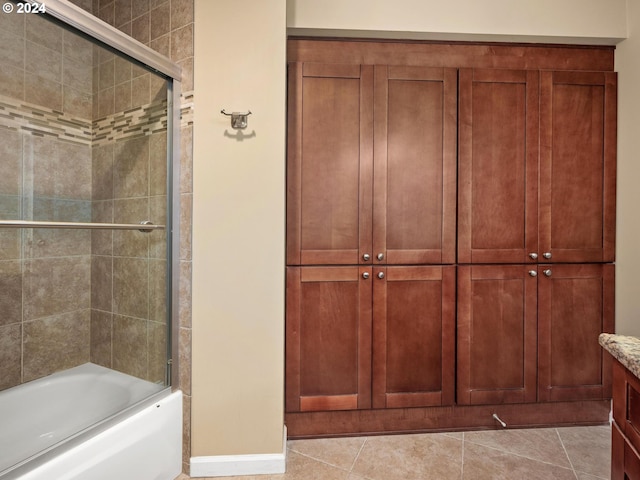 bathroom with tile patterned flooring, bath / shower combo with glass door, and vanity