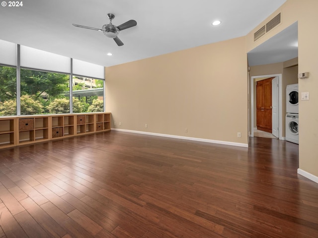 unfurnished room featuring ceiling fan, stacked washer and clothes dryer, and dark hardwood / wood-style floors