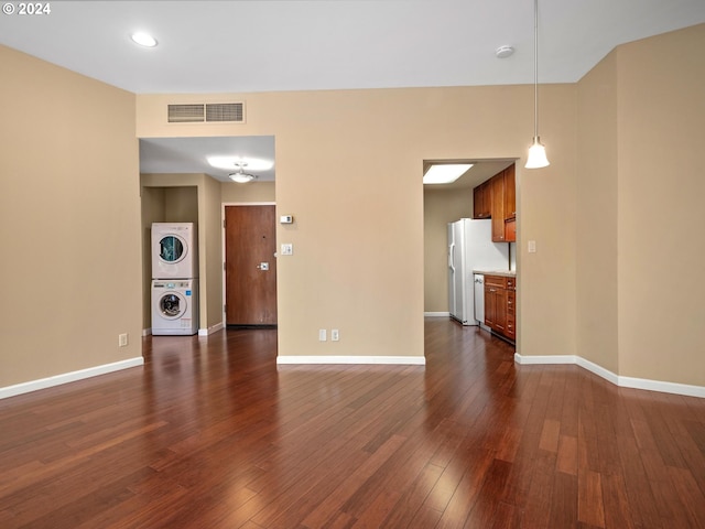 unfurnished living room featuring stacked washer and clothes dryer and dark hardwood / wood-style floors