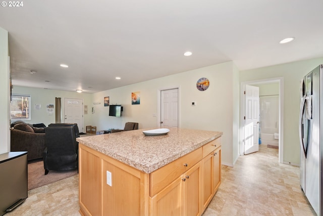 kitchen featuring stainless steel fridge, a kitchen island, and light brown cabinetry