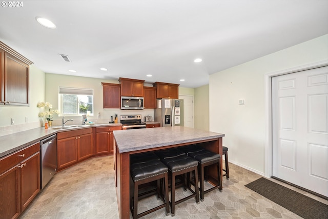 kitchen with a kitchen bar, stainless steel appliances, a kitchen island, and sink