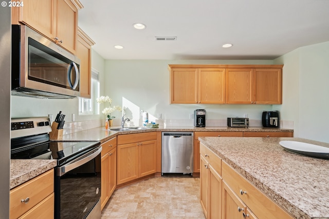 kitchen with light brown cabinetry, light stone countertops, sink, and stainless steel appliances