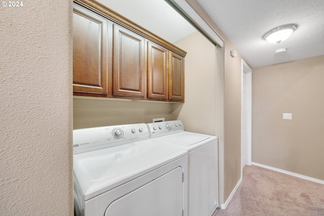 laundry area featuring cabinets, washing machine and dryer, a textured ceiling, and light colored carpet