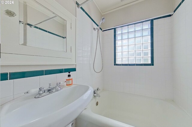 bathroom with tile walls, tasteful backsplash, sink, and tiled shower / bath