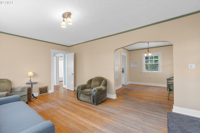 living room with crown molding, a textured ceiling, hardwood / wood-style flooring, and a notable chandelier