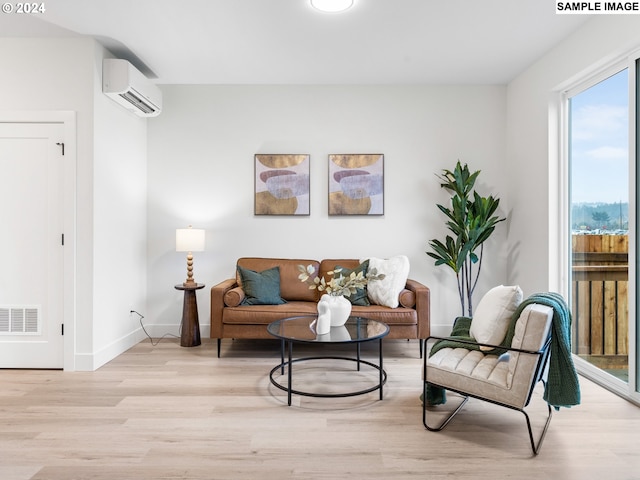 sitting room with an AC wall unit and light hardwood / wood-style flooring