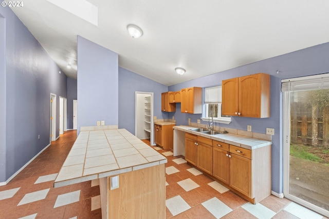 kitchen with light tile patterned floors, tile countertops, lofted ceiling, and sink