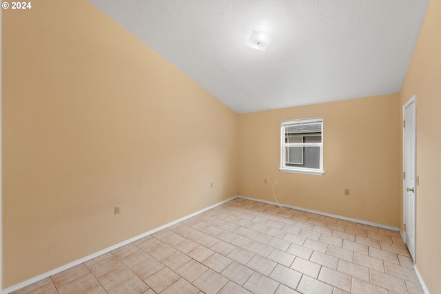 spare room with a textured ceiling and lofted ceiling