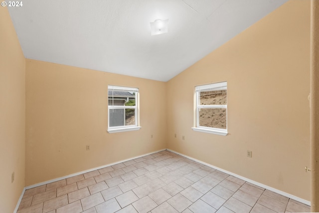 tiled spare room featuring vaulted ceiling