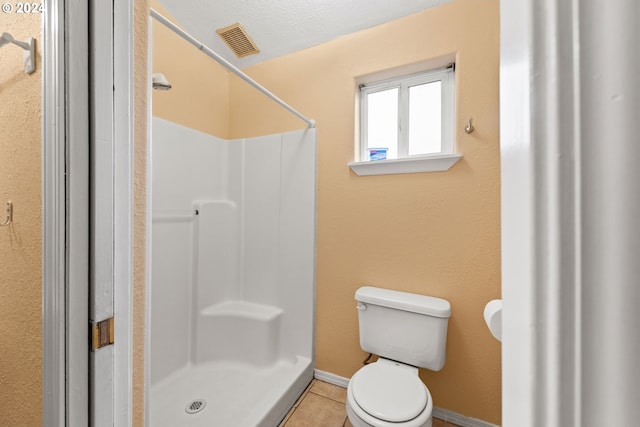 bathroom featuring tile patterned flooring, toilet, and walk in shower