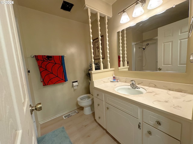 bathroom with hardwood / wood-style floors, vanity, toilet, and a shower