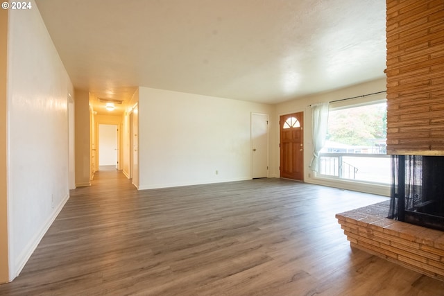 unfurnished living room featuring a fireplace, baseboards, and wood finished floors