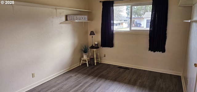 empty room with wood finished floors, visible vents, and baseboards