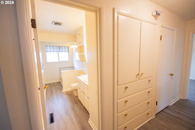 hall featuring visible vents, light wood-style flooring, and baseboards