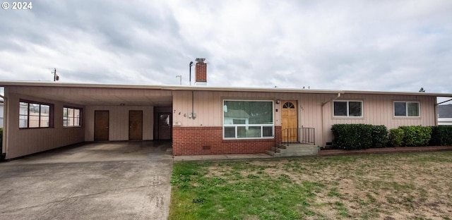 ranch-style house featuring a carport, concrete driveway, brick siding, and a chimney