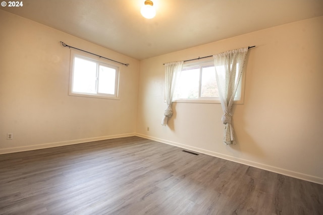 empty room with a healthy amount of sunlight, visible vents, and wood finished floors