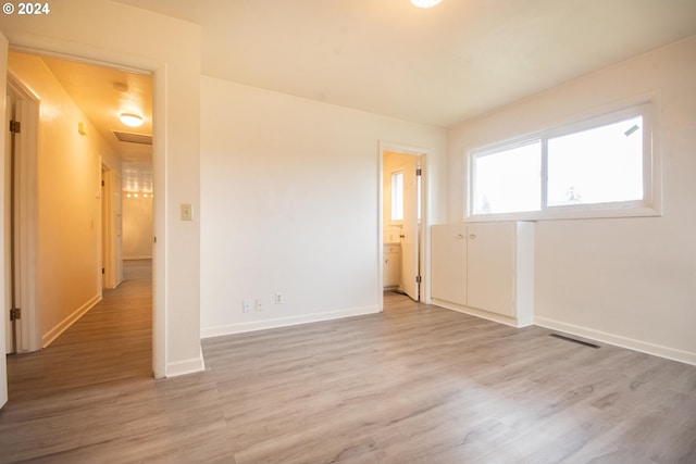 spare room featuring attic access, visible vents, baseboards, and wood finished floors