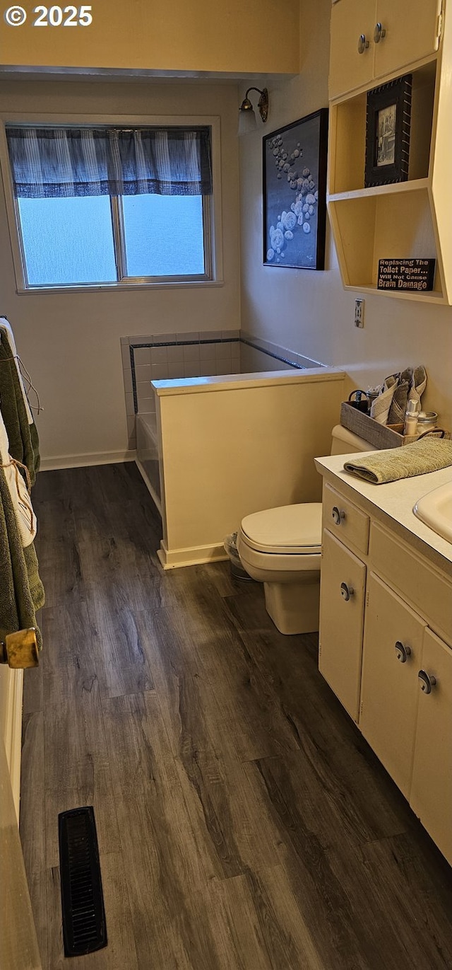 bathroom featuring toilet, wood finished floors, vanity, visible vents, and a wealth of natural light