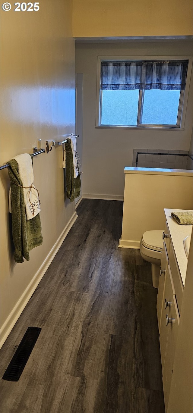 bathroom with baseboards, visible vents, toilet, wood finished floors, and vanity