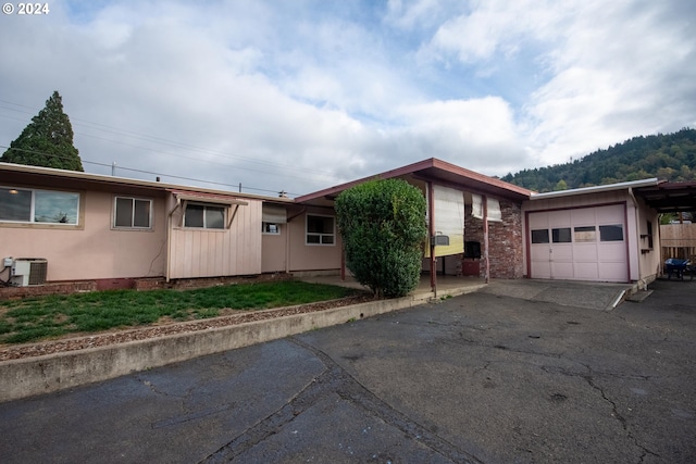 ranch-style home with a garage, central AC, and aphalt driveway