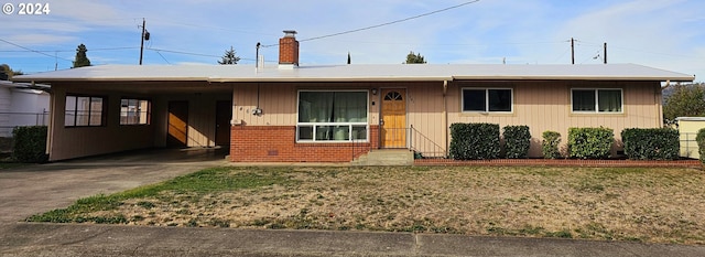 ranch-style home featuring a carport, a front yard, concrete driveway, and brick siding