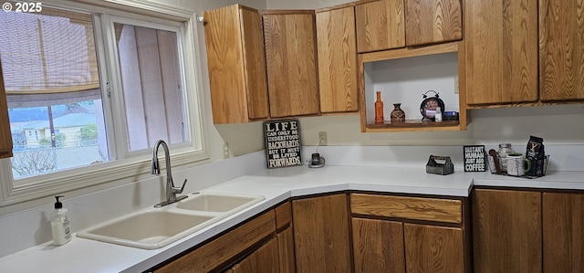 kitchen featuring brown cabinetry, light countertops, and a sink