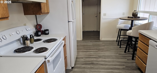 kitchen featuring under cabinet range hood, dark wood-type flooring, electric stove, light countertops, and brown cabinetry