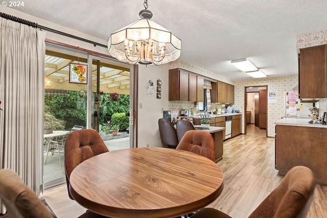 dining space with a wealth of natural light, a chandelier, a textured ceiling, and light wood-type flooring