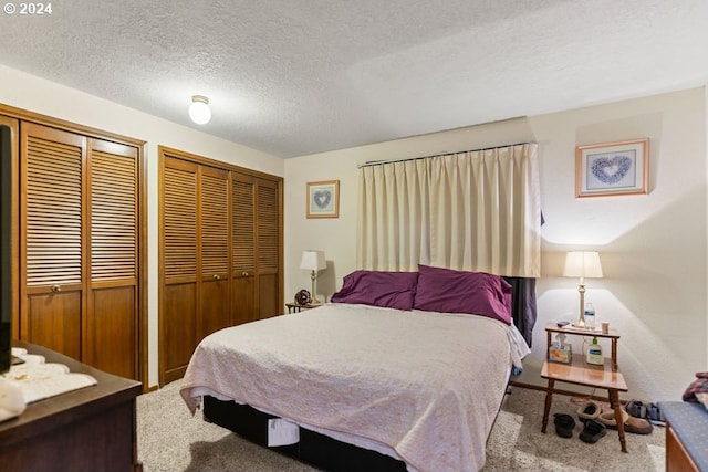 bedroom featuring carpet floors, a textured ceiling, and multiple closets