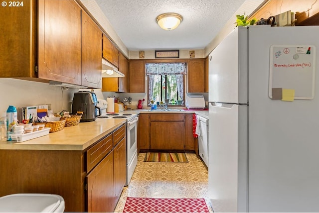 kitchen with a textured ceiling, sink, and white appliances