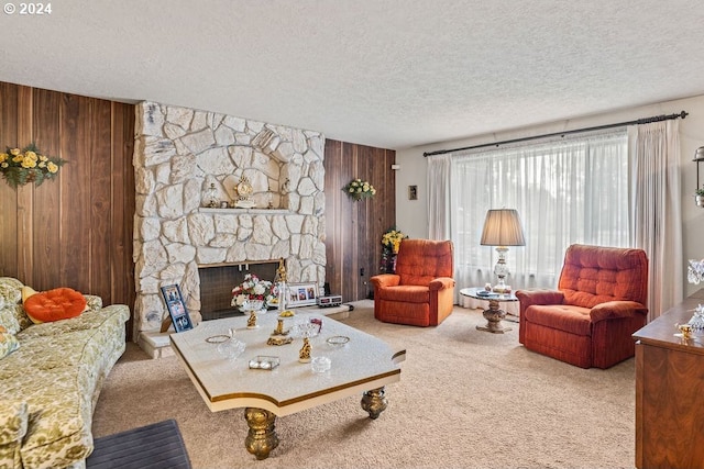 living room featuring carpet, wood walls, a textured ceiling, and a stone fireplace