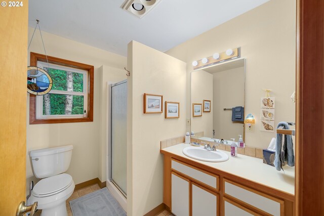 bathroom featuring walk in shower, vanity, tile patterned flooring, and toilet