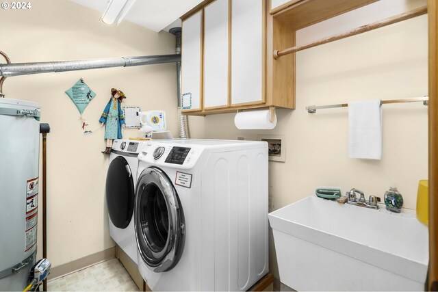 clothes washing area with cabinets, water heater, independent washer and dryer, and sink