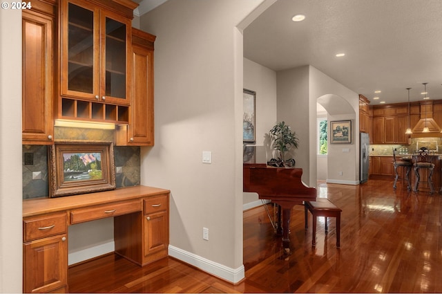 home office featuring built in desk and dark hardwood / wood-style flooring