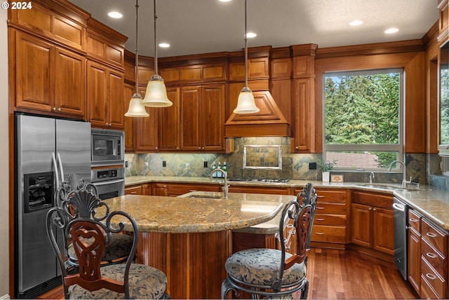 kitchen with appliances with stainless steel finishes, a center island with sink, pendant lighting, a breakfast bar, and sink