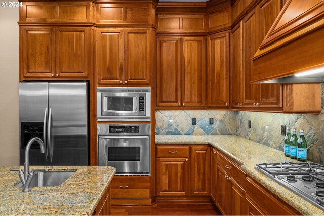 kitchen with light stone counters, stainless steel appliances, decorative backsplash, and sink