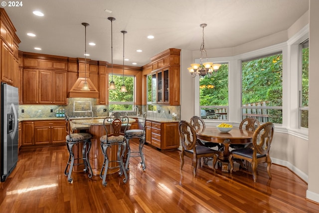 dining space featuring a tiled fireplace, hardwood / wood-style floors, crown molding, and an inviting chandelier