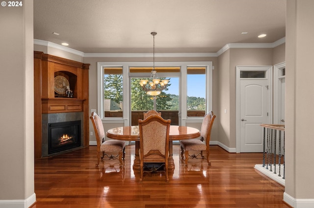 dining room with a fireplace, a chandelier, crown molding, and hardwood / wood-style floors