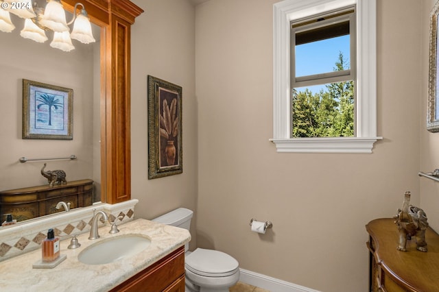 bathroom featuring toilet, vanity, and a notable chandelier