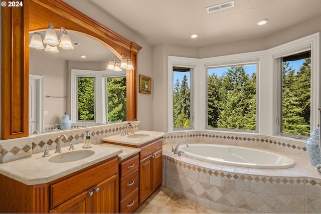 bathroom with vanity, tasteful backsplash, a healthy amount of sunlight, and tiled tub