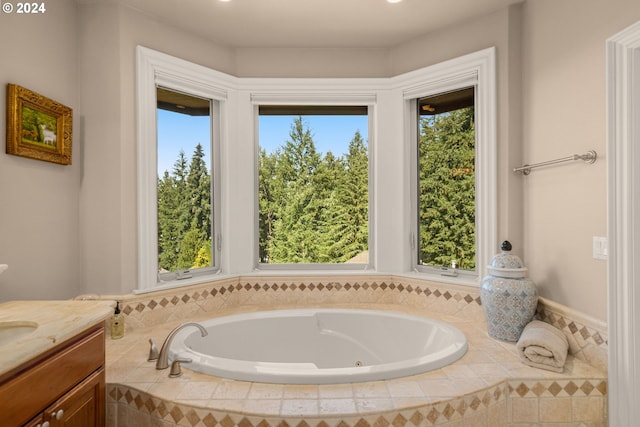 bathroom with vanity, a healthy amount of sunlight, and tiled tub